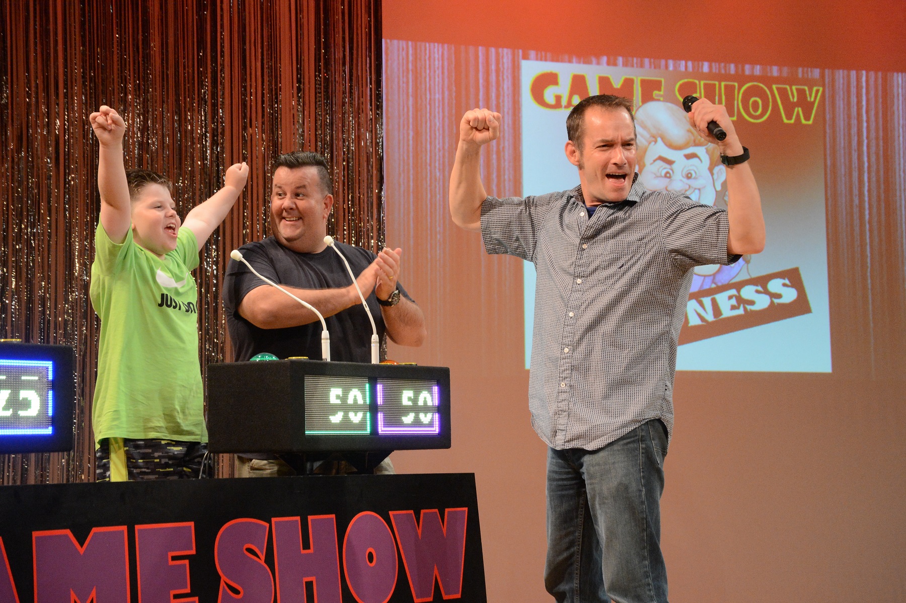 Game Show contestants  at game show pedestals on stage showing excitement and enthusiasm