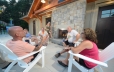Guests are seated around and in front of a stone fireplace that is built into the wall. In the background of the photo a portion of the splash pad is shown.