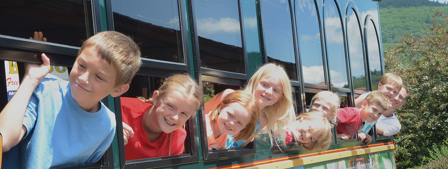 Children smiling looking out trolley windows