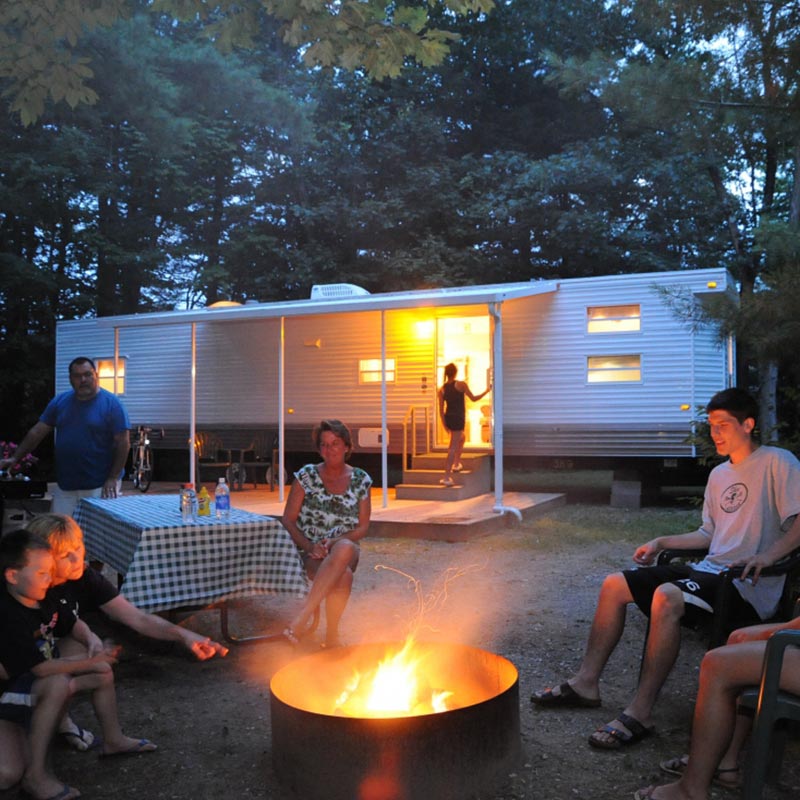 Family enjoying time by the campfire in front of one of our RV rentals