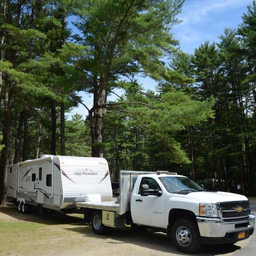 RV trailer connected to truck, backing into campsite