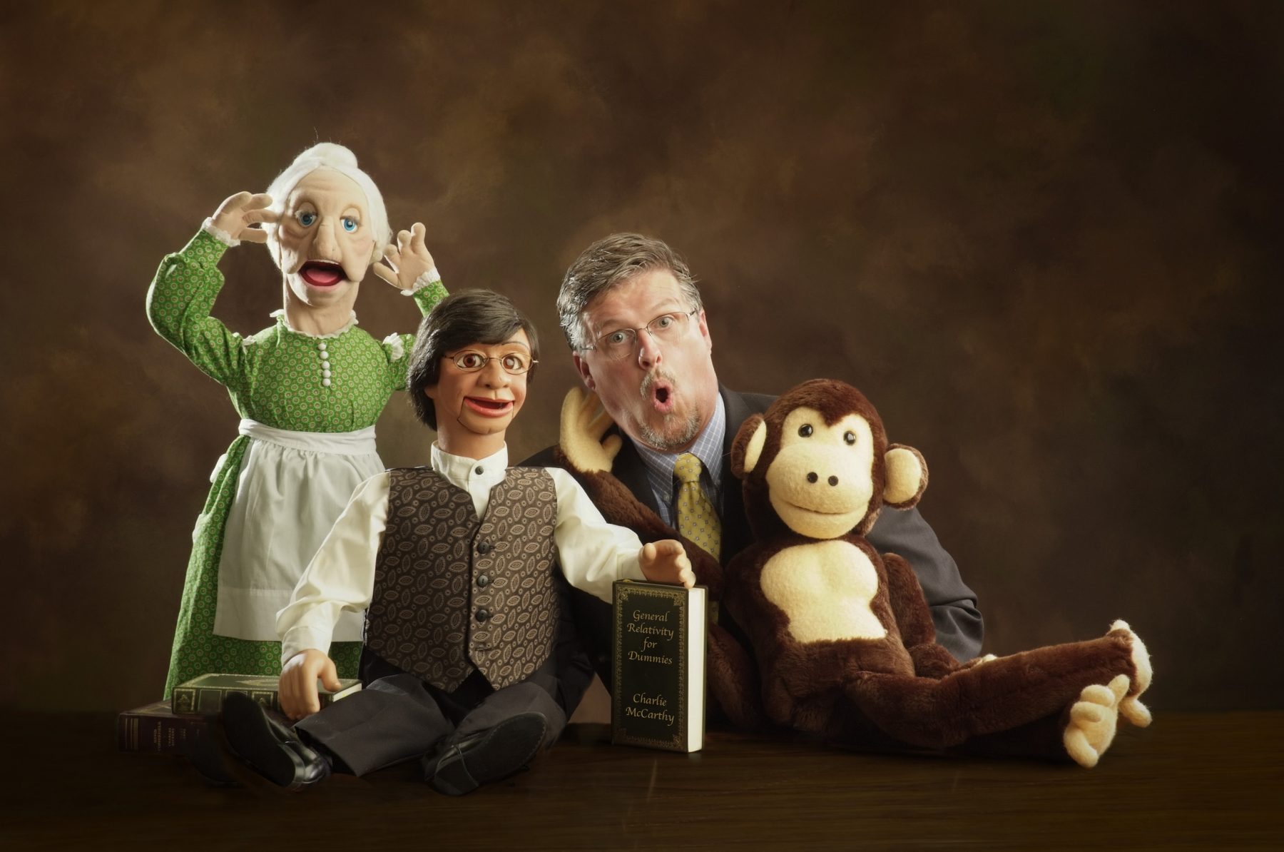Ventriloquist poses with three puppets