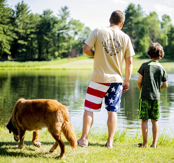 Father and son with dog fishing in pond