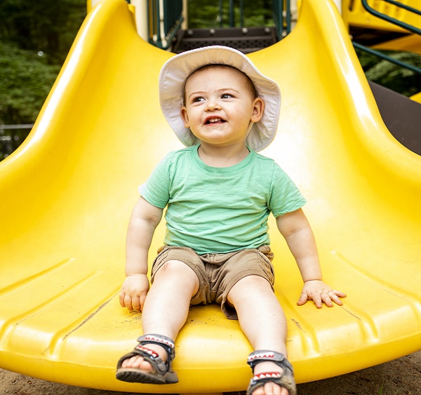 Toddler sitting on the end of yellow slide