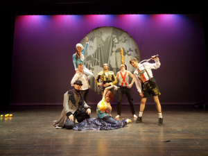 French Mountain Playhouse artists, Acrobats of Cirequetacular. The 7 artists are dressed in miscelleanous outfits and posing on stage.