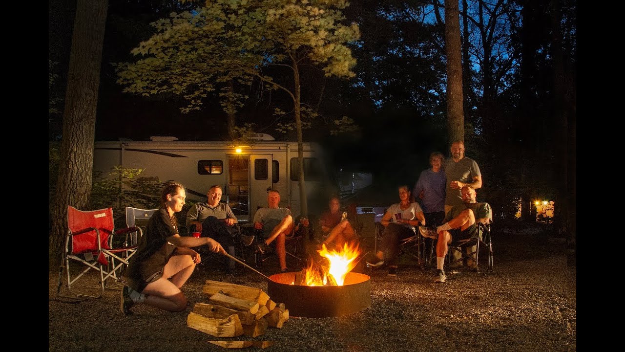 Family sitting around campfire on their site and roasting marshmallows